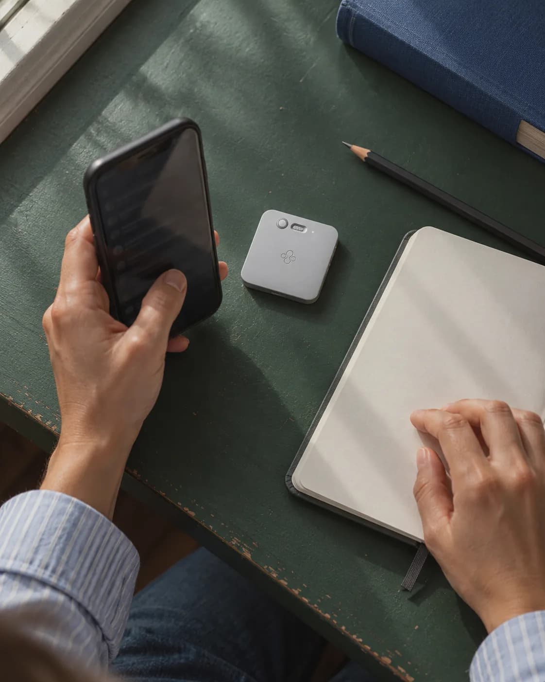 Hand holding a phone above a desk, with Jase Slate beside a notebook