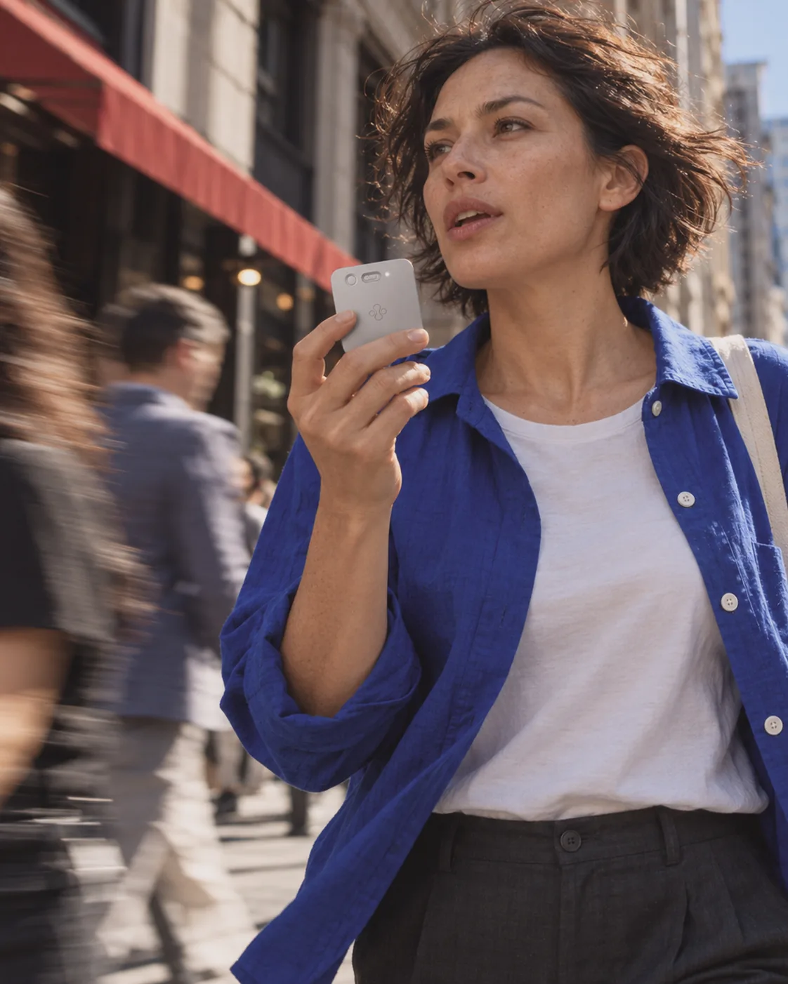 Woman speaking a voice note into Jase Slate while walking down a busy city street
