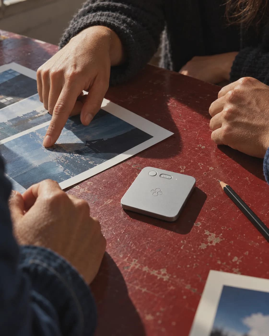 Colleagues pointing at printed photos on a meeting table, with a silver Jase Slate beside them